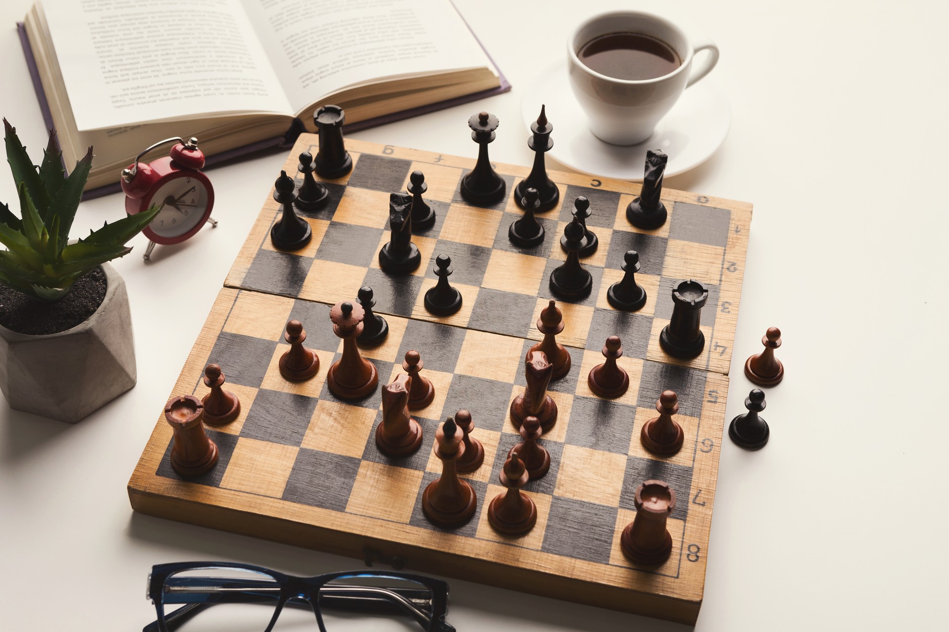 Wooden desk with chess play, book and coffee cup